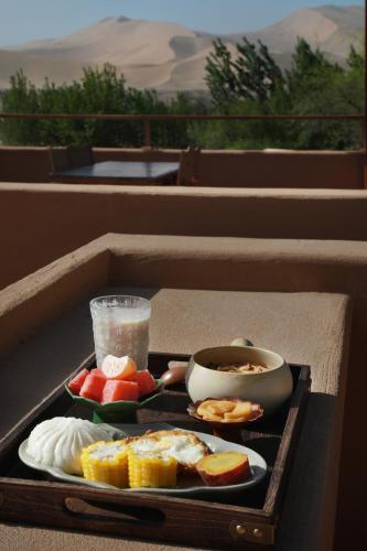a tray of food with eggs and fruit and a drink at DunHuang FengMingSha Hotel in Dunhuang