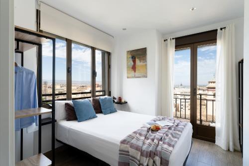 a bedroom with a large white bed and large windows at Mirador del Zenete in Granada