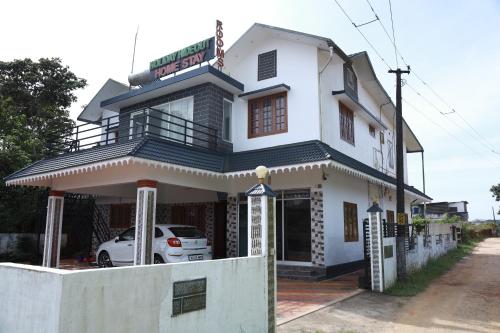 a white house with a car parked in front of it at HOLYDAy HIDEOUT in Vandanmedu