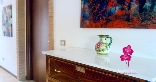 a vase sitting on top of a dresser under a painting at Residenza Locci - Rooms & Apartments in Teulada