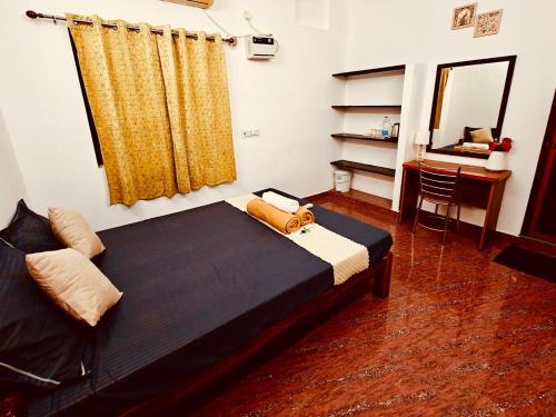 a bedroom with a bed and a desk and a mirror at Villa de Compass Homestay Auroville in Kottakupam