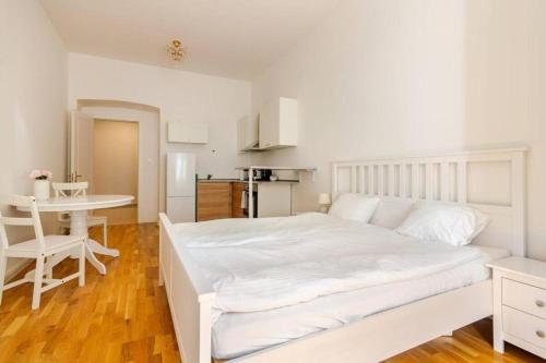 a white bedroom with a white bed and a table at Beautiful Apartment by Stromovka Park in Prague