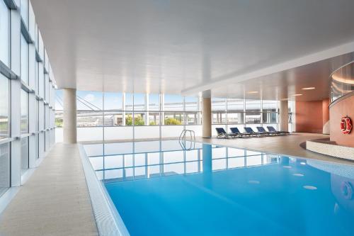 une grande piscine dans un immeuble avec une grande fenêtre dans l'établissement Sheraton Milan Malpensa Airport Hotel & Conference Centre, à Ferno