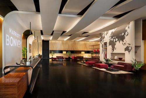 a lobby of a building with red chairs at Sheraton Milan Malpensa Airport Hotel & Conference Centre in Ferno