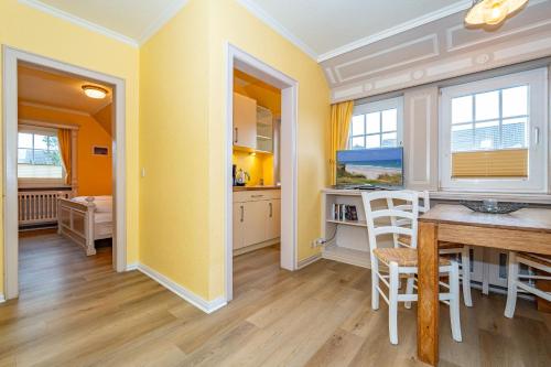 a kitchen and dining room with yellow walls and a table at Priel-Hüs in List