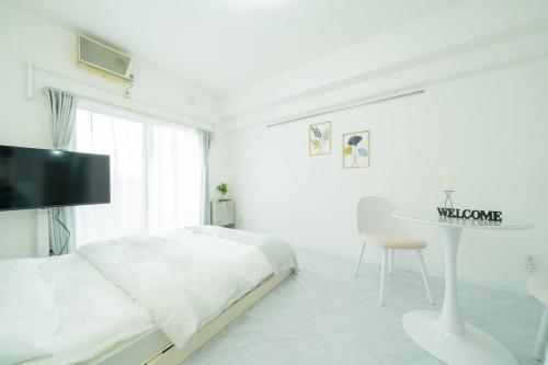 een witte slaapkamer met een bed en een tafel bij Maison de Grue 601 in Sapporo