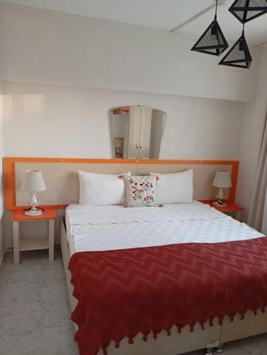 a bedroom with a large bed with a red blanket at NEŞELİ APART BAHÇE CAFE in Seferihisar