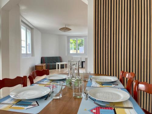 a dining room table with plates and glasses on it at Le Cosy Tranchais - city center - 300 m beach in La Tranche-sur-Mer