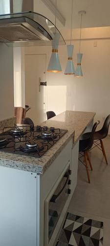 una cucina con fornelli e un bancone con sedie di Espanha Residence a Florianópolis
