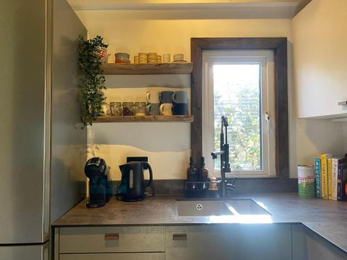 a kitchen counter with a sink and a window at Hunters Cabin - Rustic farm stay in Great Chart
