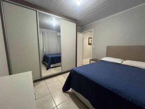 a bedroom with a blue bed and a mirror at Casa de 03 dormitórios no centro de Bombinhas in Bombinhas