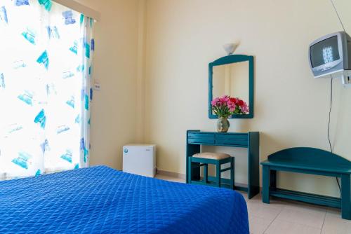 a bedroom with a blue bed and a table and a mirror at Panorama Hotel in Agia Marina Aegina