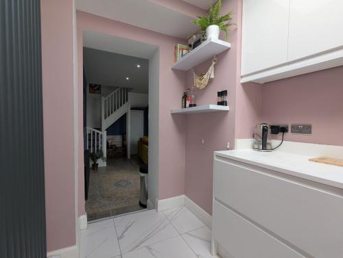 une cuisine avec des murs roses et des comptoirs blancs dans l'établissement Heart of Hove Modern House, à Brighton et Hove