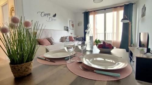 ein Wohnzimmer mit einem Tisch mit Tellern und Weingläsern in der Unterkunft L'Eure Au Soleil, avec balcon et Wifi in Évreux