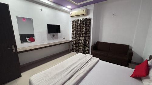 Un dormitorio con una cama, un sofá y un televisor. en Hotel O Green Park, en Ambaji
