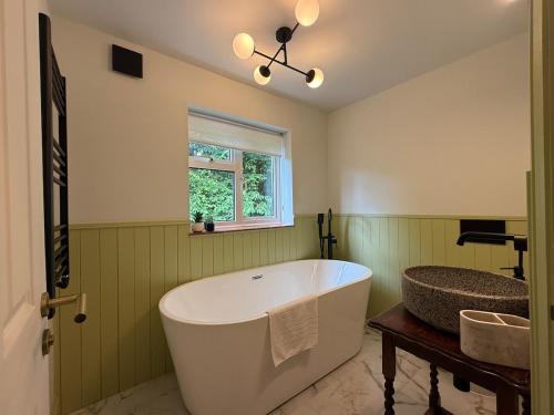 una grande vasca da bagno in un bagno verde con una finestra di Spacious Forest Row Home by Ashdown Trails a Forest Row
