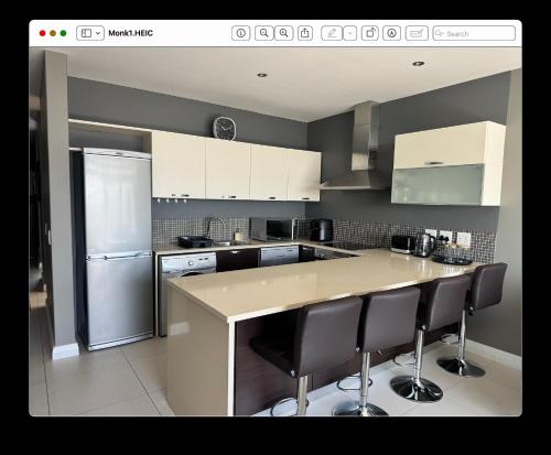 a kitchen with a refrigerator and a counter with bar stools at 22 Monks View in Plettenberg Bay