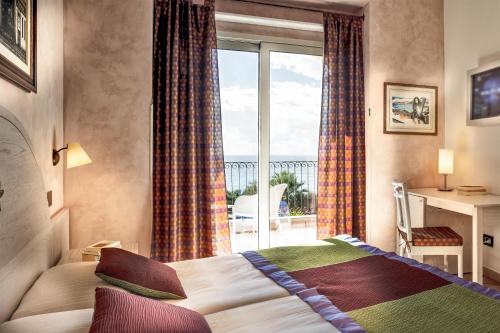 a bedroom with a bed and a large window at Hotel Stella Maris in Villasimius