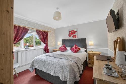 a bedroom with a bed with red pillows on it at Greyhound Country Inn in Honiton