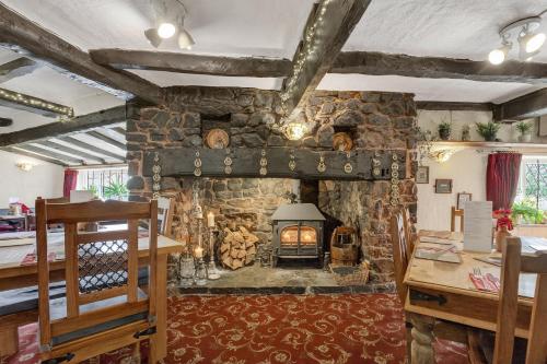 Una gran chimenea de piedra en una habitación con mesa. en Greyhound Country Inn, en Honiton
