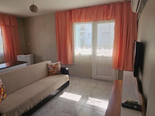 a living room with a couch and a window at NEŞELİ APART BAHÇE CAFE in Seferihisar