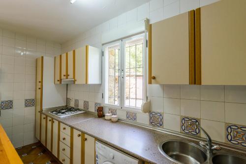 a kitchen with yellow cabinets and a sink and a window at Casa Jurinea in Torres