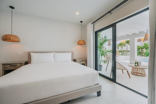 a bedroom with a white bed and a large window at NEW 6 Bed 6 Bath Pool - Bocobay Mangel Beach House in Savaneta