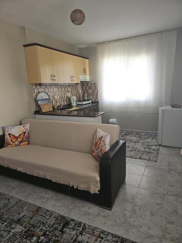 a living room with a couch and a kitchen at NEŞELİ APART BAHÇE CAFE in Seferihisar