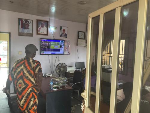 a man standing in front of a desk with a television at Otam homes in Akure
