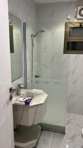 a white bathroom with a shower and a sink at شقة بغرفتين نوم وصالة بدخول ذكي in Al Madinah