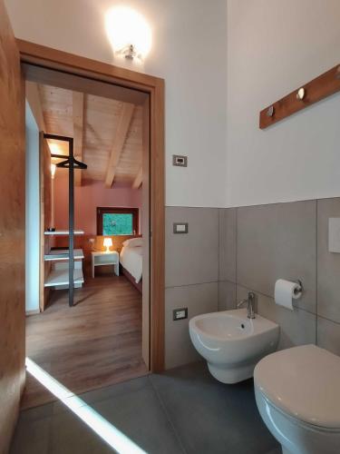 a bathroom with a sink and a toilet and a bedroom at Agriturismo Il Contadino Simo - Dolomites Farmhouse in Mis