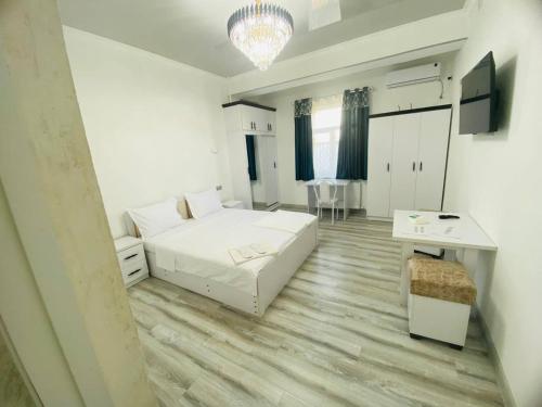 Una habitación blanca con una cama, un escritorio y un televisor. en Mellinium apartment free pick up drop off, en Bukhara