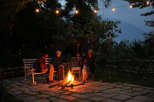 un grupo de personas sentadas alrededor de un fuego por la noche en Unwind at Chanderlok, en Nagar