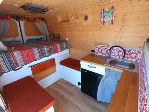 Una cocina con fregadero y una cama en una habitación. en Descubre Tenerife en furgoneta camper, en Los Abrigos