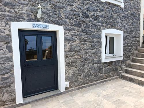 a front door of a house with a stone wall at Adelaide's Cottage in Ponta do Pargo
