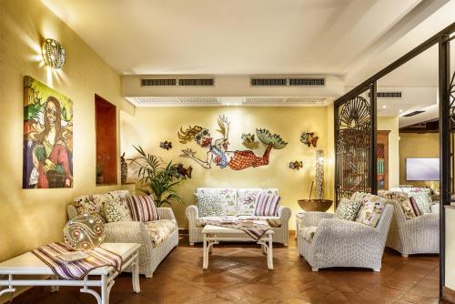 a living room with couches and chairs and paintings at Hotel Stella Maris in Villasimius