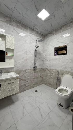 a white bathroom with a toilet and a sink at Moy goust house in Qusar
