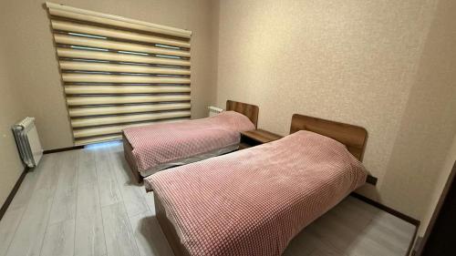 two beds in a room with a window at Moy goust house in Qusar