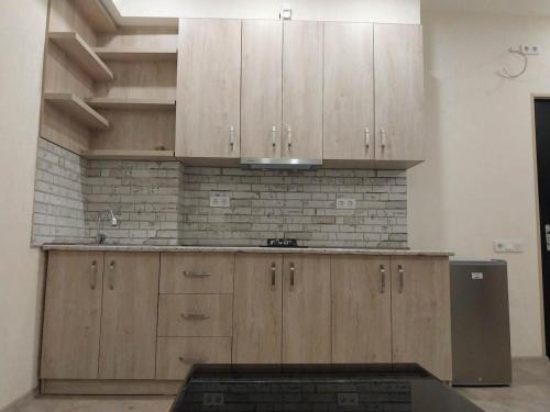une cuisine avec des placards en bois et un mur en briques dans l'établissement Apart Fenix, à Stantsiya Mukhiani