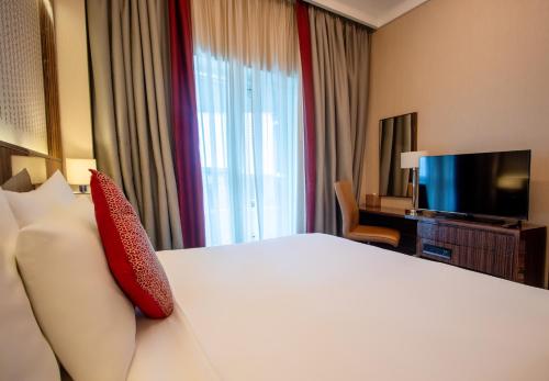 a hotel room with a bed and a television at Naumi Hotel Dubai - formerly dusitD2 Kenz in Dubai