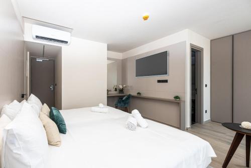 een slaapkamer met een wit bed en een tv aan de muur bij Warner Boutique Hotel Adults only in Larnaka