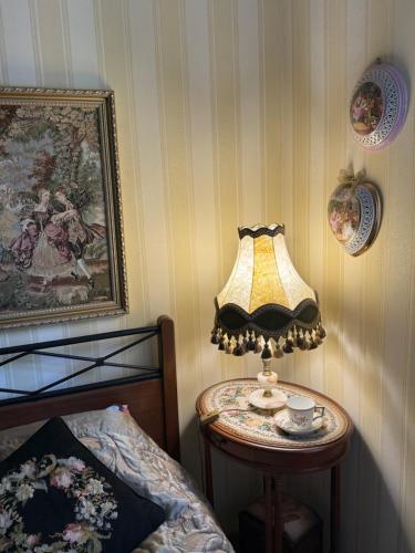 a lamp sitting on a table next to a bed at Central Antique Gallery Apartment by the River -Self Check-in in Klaipėda