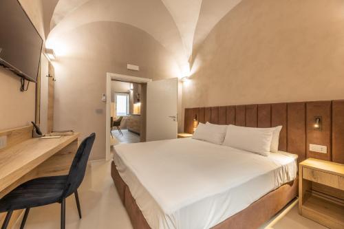 Dimora Suite Argento في غالّيبولي: غرفة نوم بها سرير أبيض كبير ومكتب