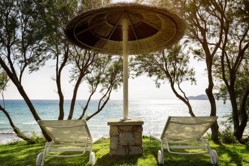 - deux chaises et un parasol en face de l'océan dans l'établissement Stella Maris, à Villasimius