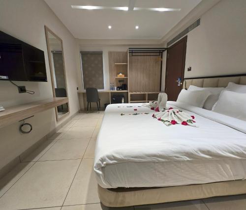 a hotel room with a large white bed with flowers on it at Aarambh By The Sky Imperial Indore in Indore