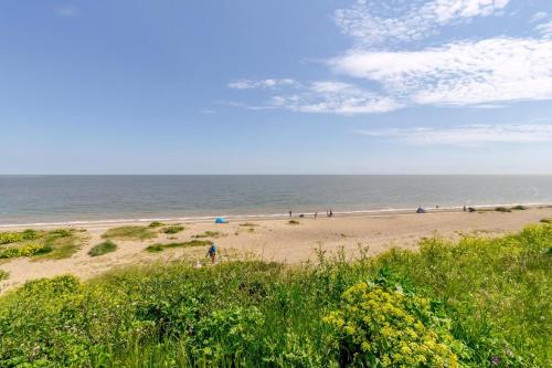 a beach with people walking on the sand and the ocean at Dog Friendly 6 Berth Caravan With Decking Close To Pakefield Beach Ref 68106Cr in Pakefield