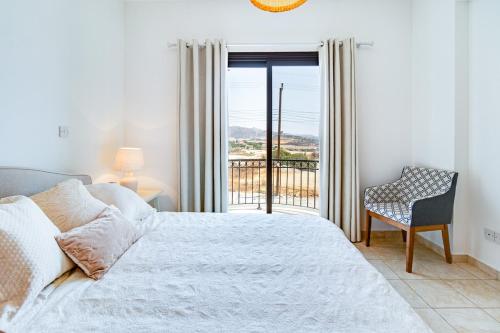 a bedroom with a bed and a chair and a window at 4 Bedroom Villa With Private Pool in Maroni