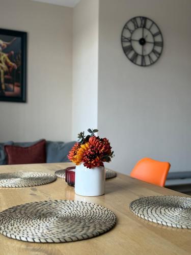 a table with a vase of flowers on top of it at Stylish and Bright 2 Bedroom Flat Free Parking in Wallasey