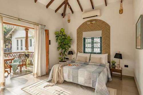 a bedroom with a large bed and a patio at Sanctuary by RÊVE in Siolim