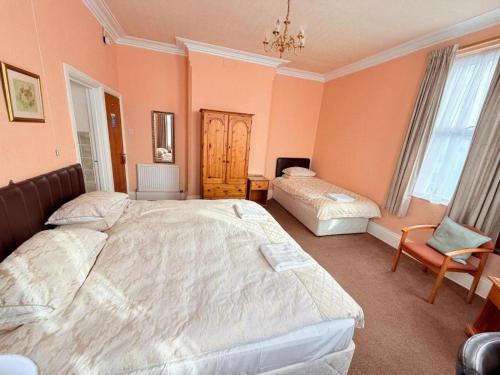 a bedroom with two beds and a chair at Hylands Hotel Spacious & Bright Triple Room with Ensuite Bathroom and Free Parking in Nottingham